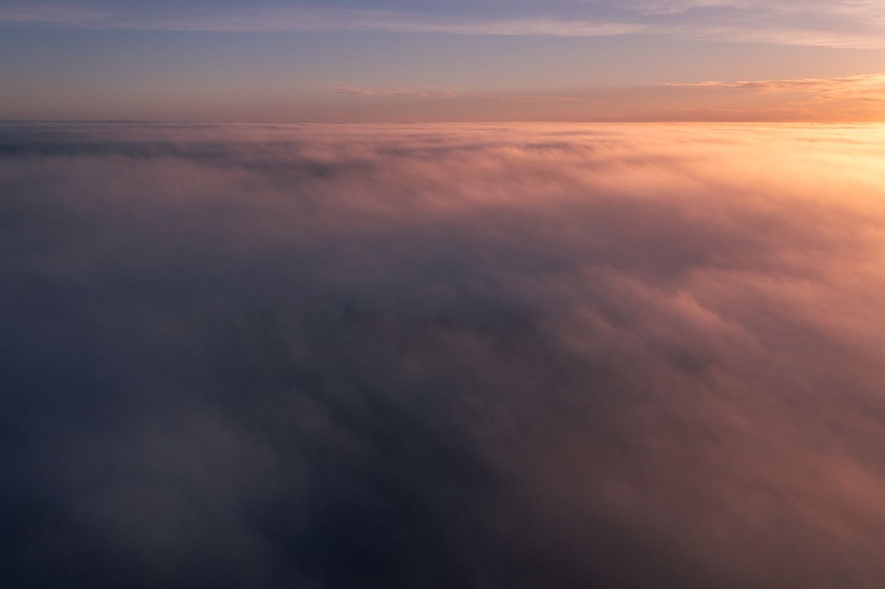services-01 A breathtaking aerial view of clouds illuminated by the warm hues of a sunset, capturing tranquility.