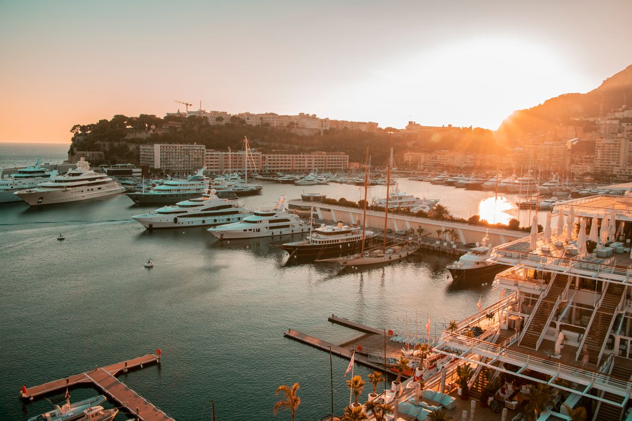 about-us Stunning view of yachts in Monaco harbor at sunset, showcasing luxury and tranquility.
